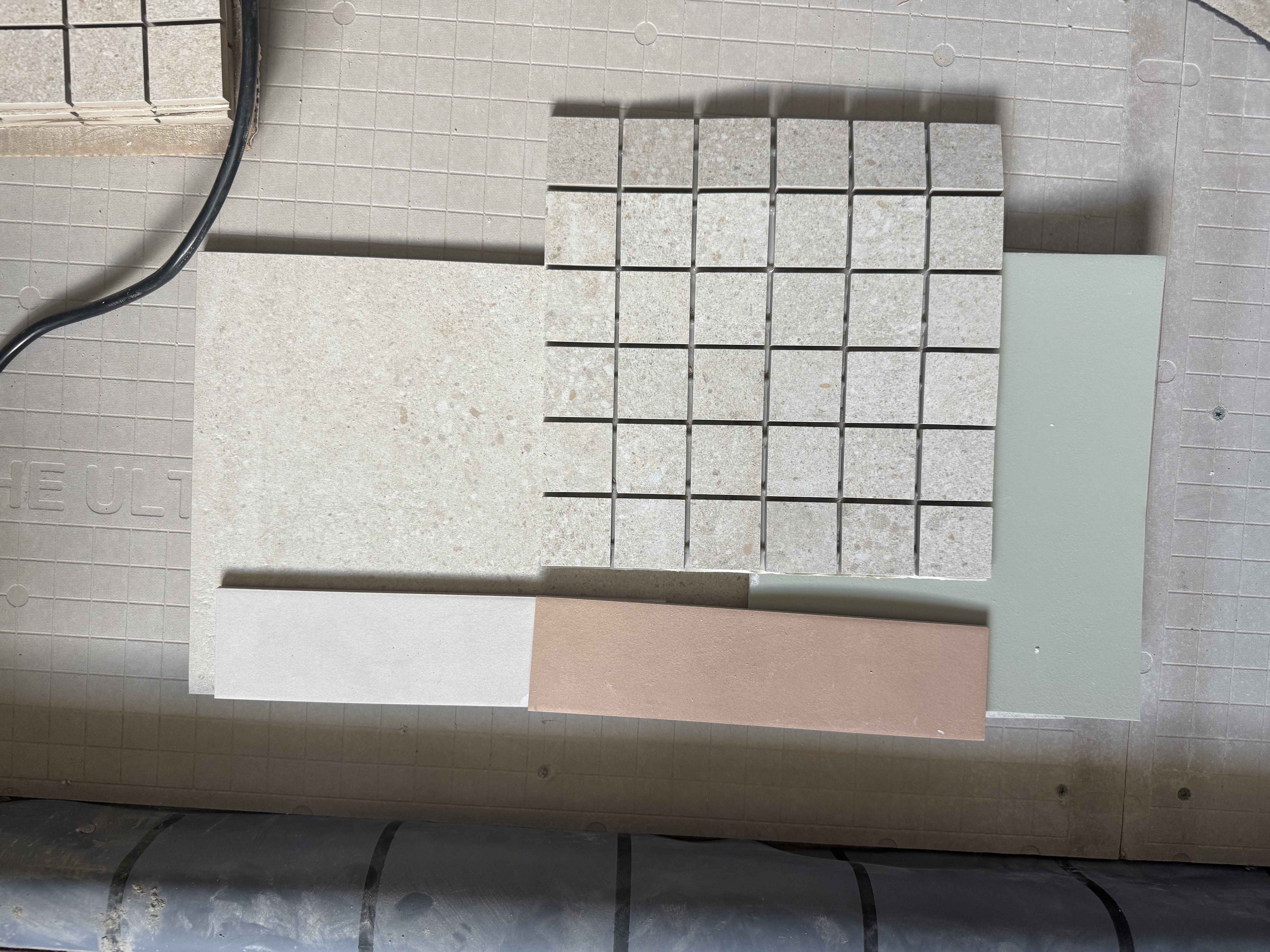 On-site finish selections — tile samples, paint chips, and stone laid out on the floor