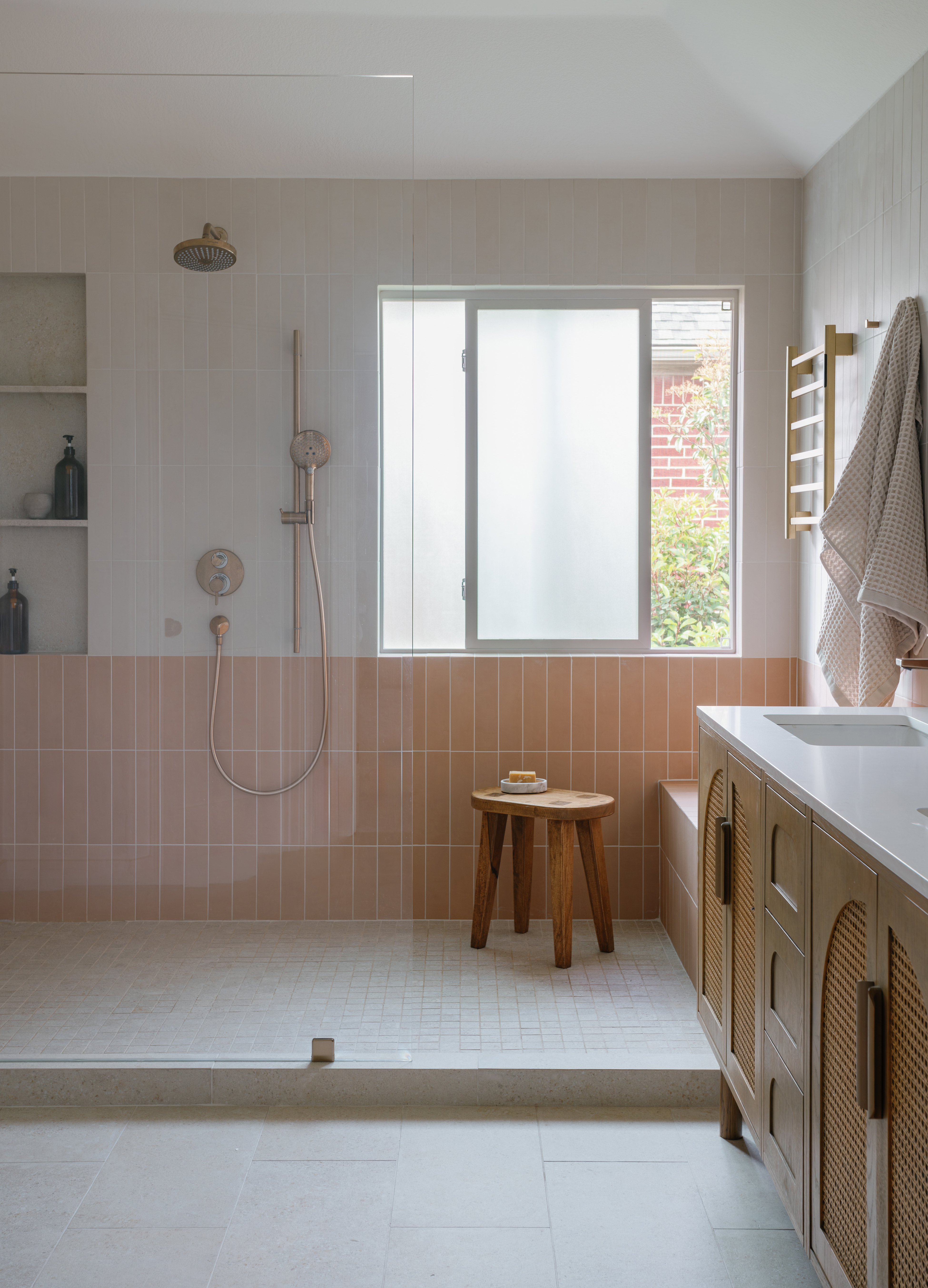 Completed primary bathroom with peach tile, walk-in shower, and cane vanity