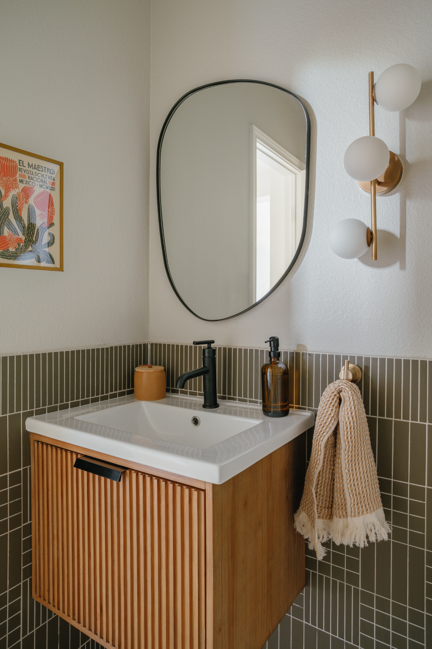 Bathroom with green tile and organic mirror