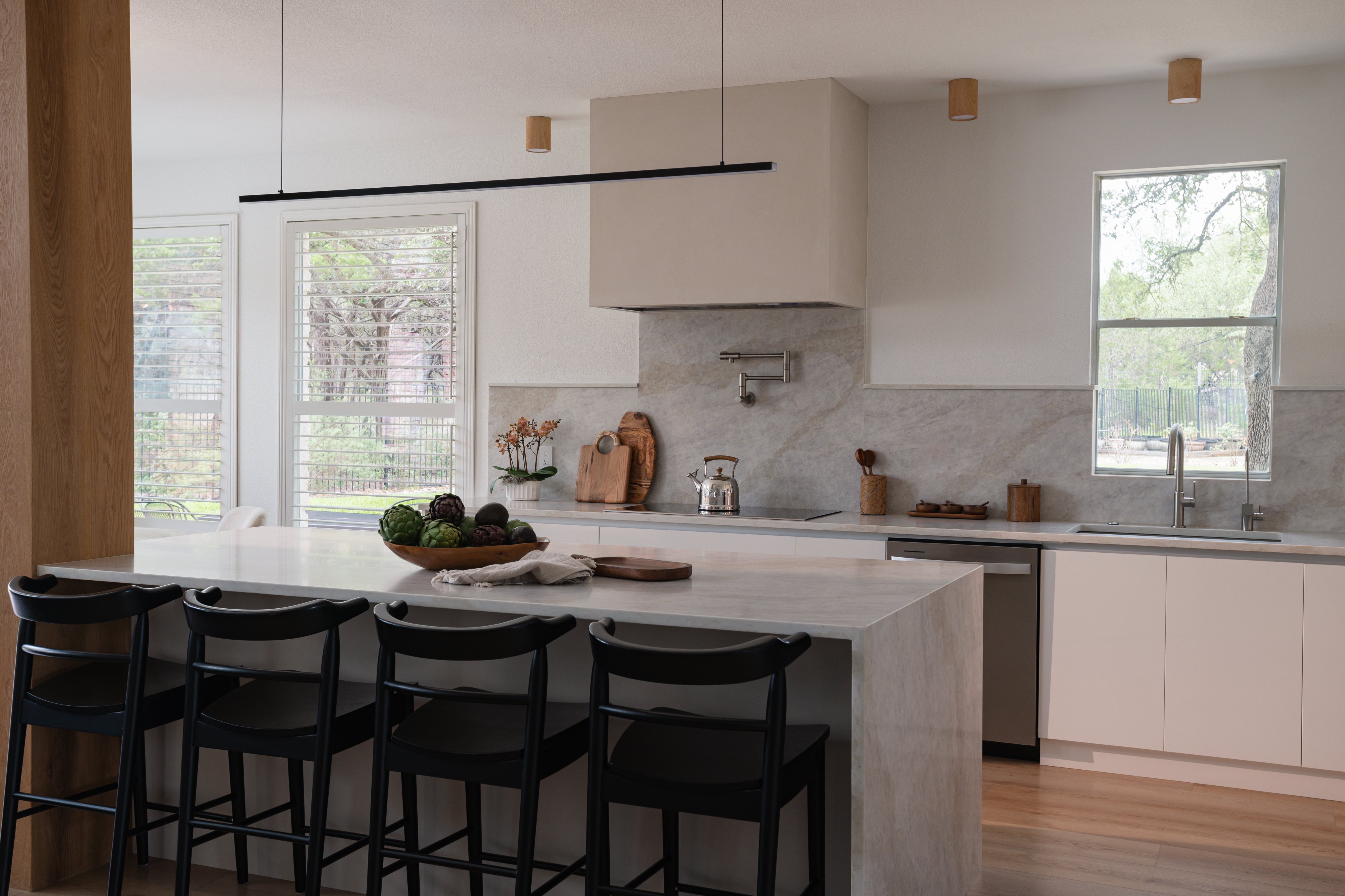 Marble waterfall island with black stools
