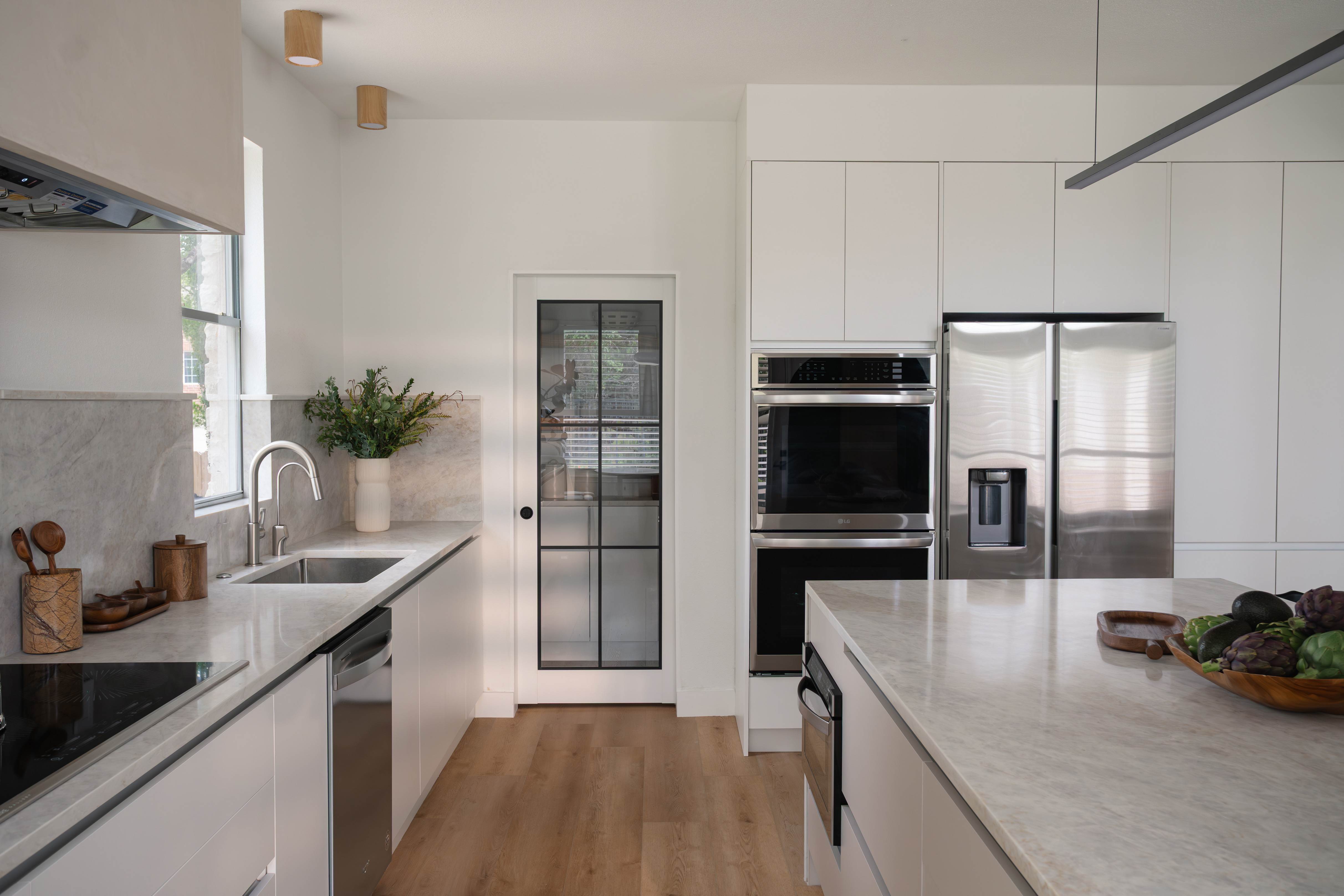 Kitchen with double ovens, fridge, and glass pantry door after the remodel