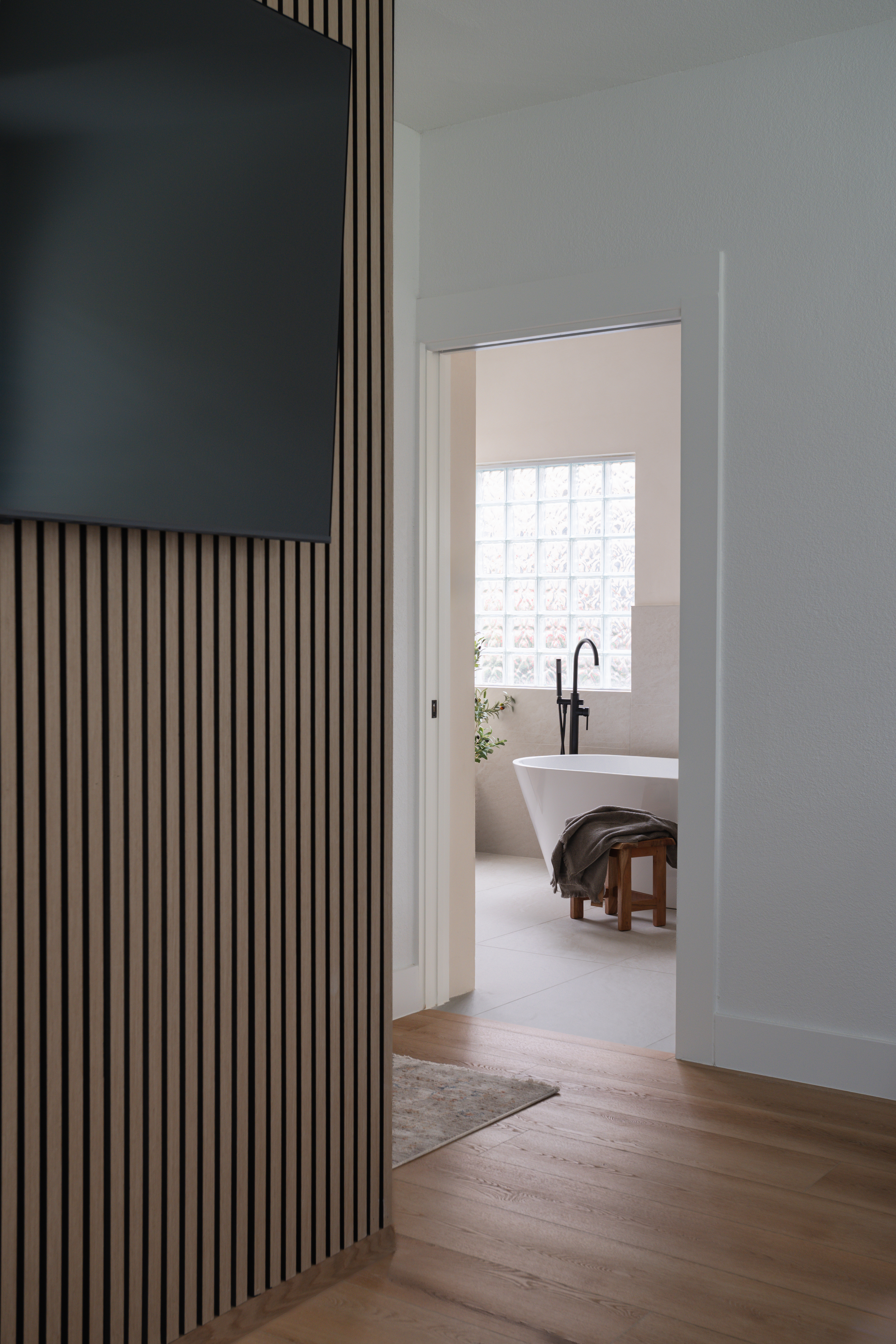 Bedroom slat wall with view through to the ensuite tub