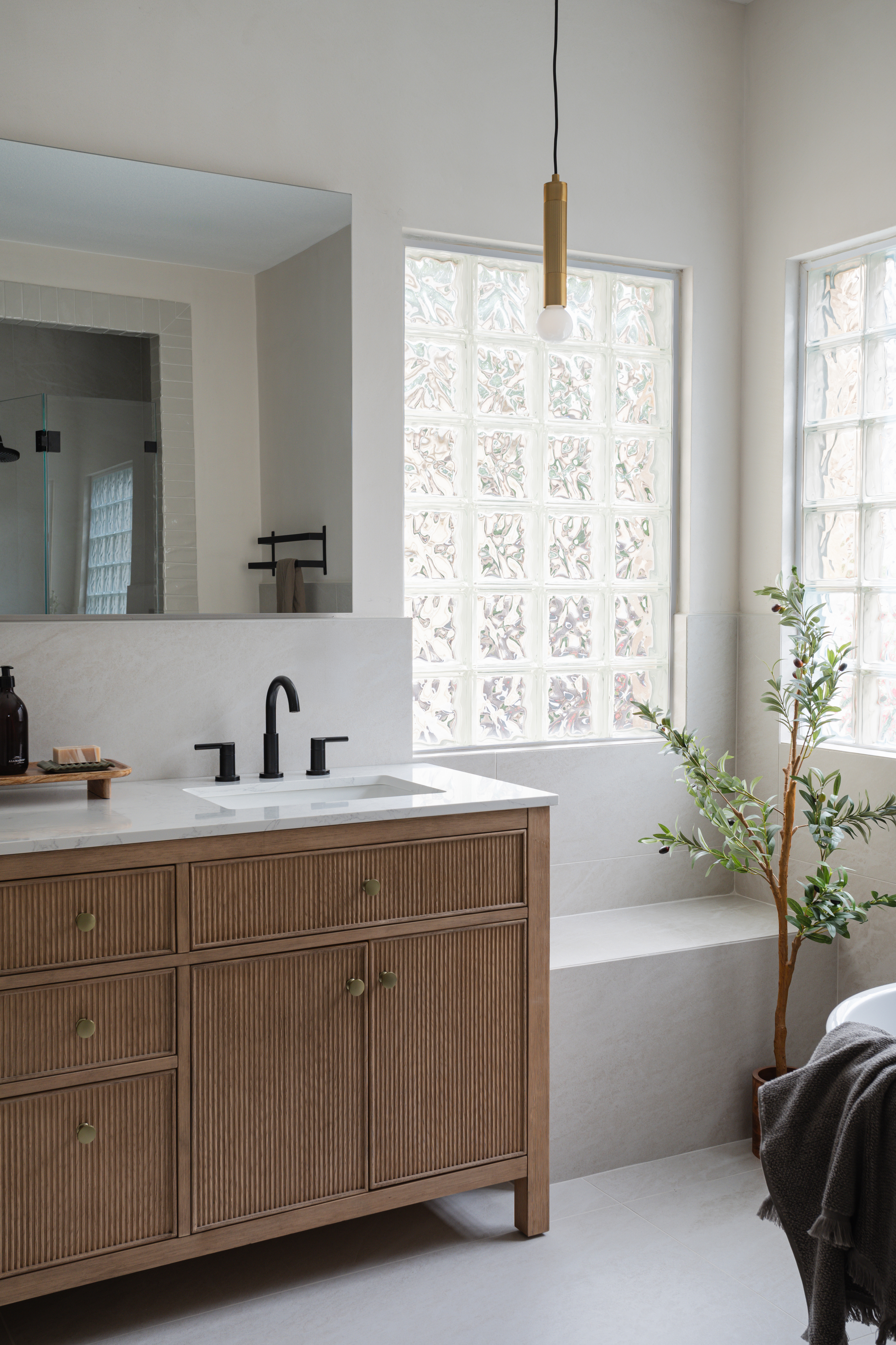 Fluted vanity beside tub and glass-block windows