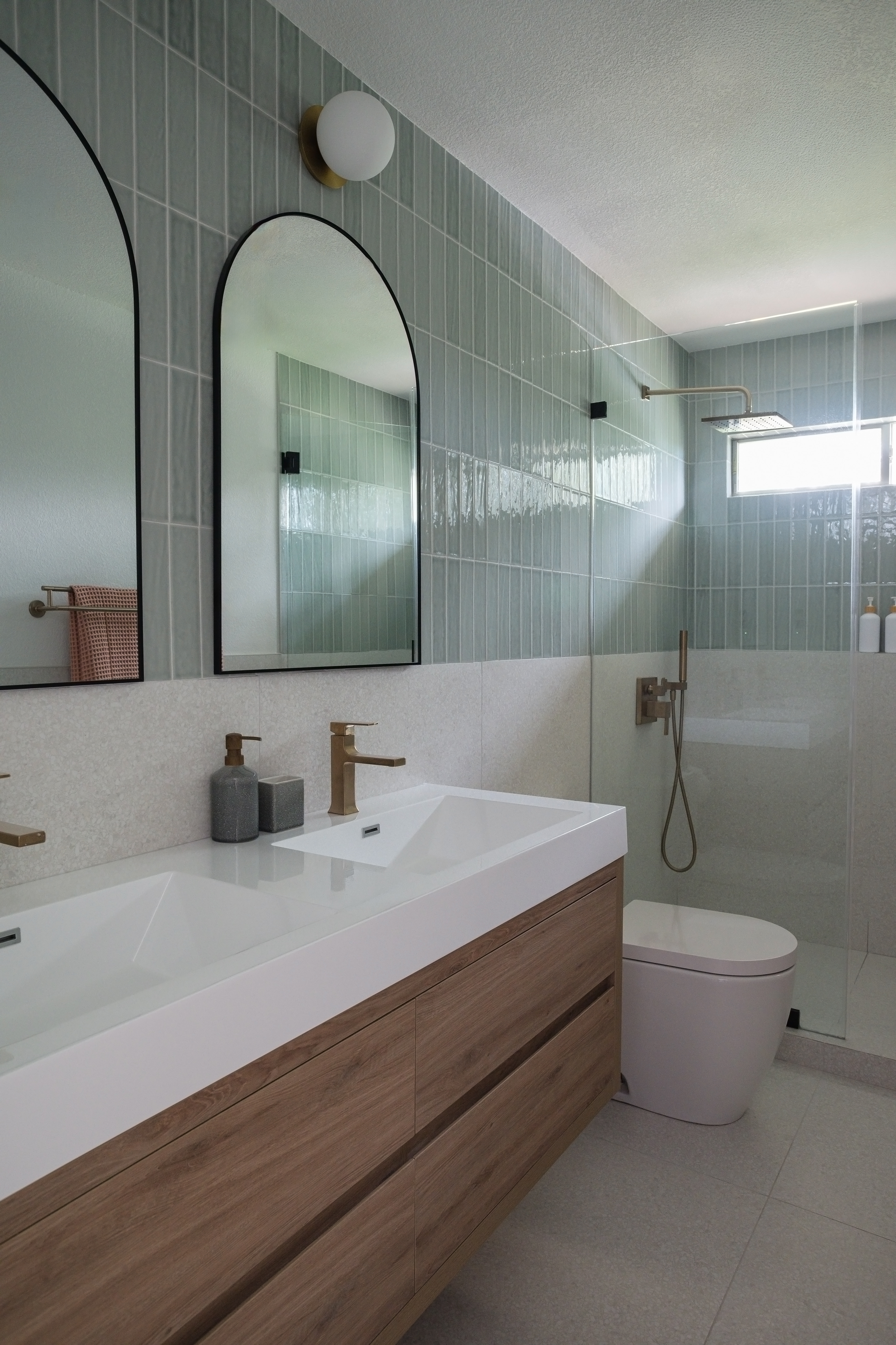 Green zellige bathroom with arched mirrors and walk-in shower after the remodel