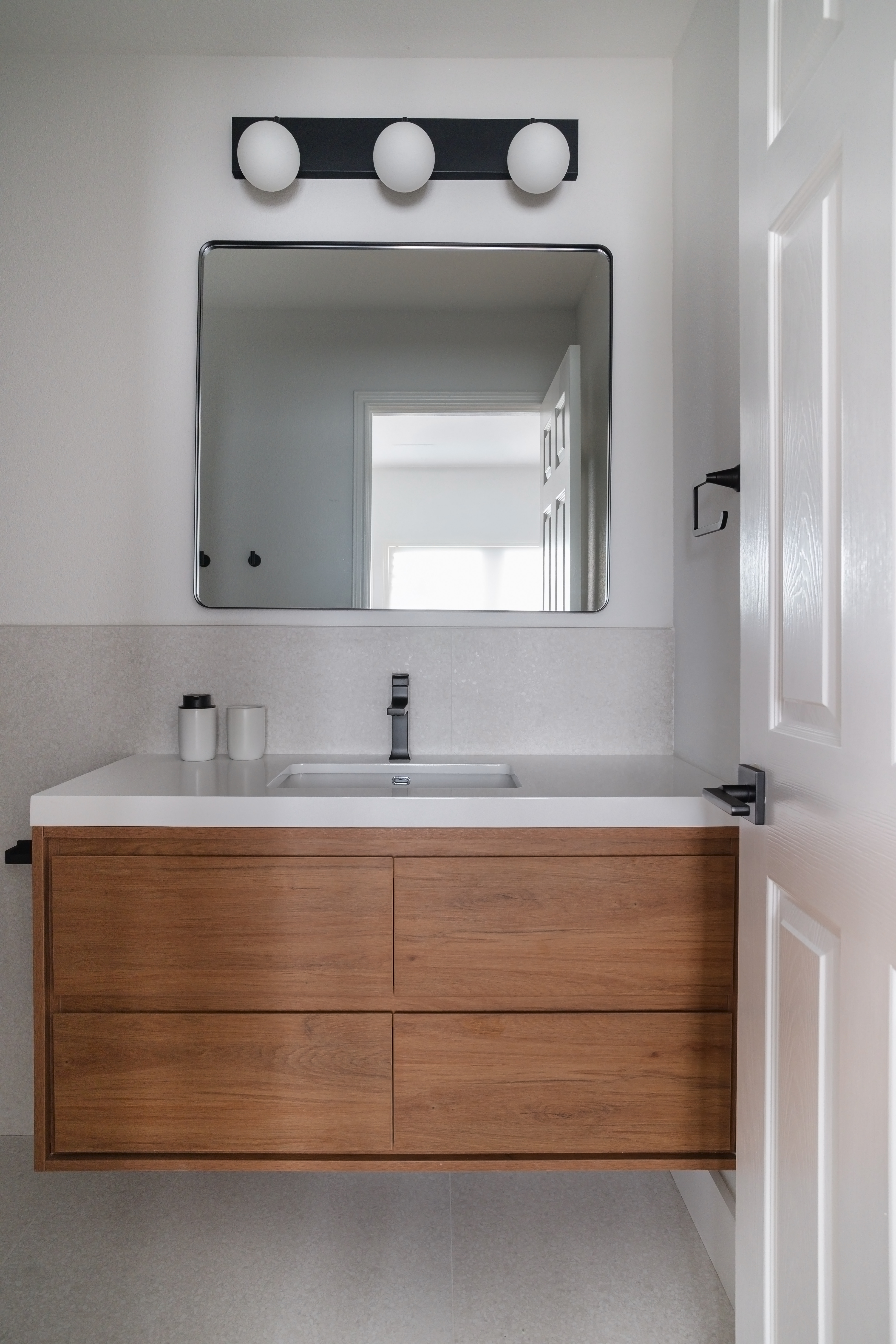 Powder room with oak vanity and globe sconces